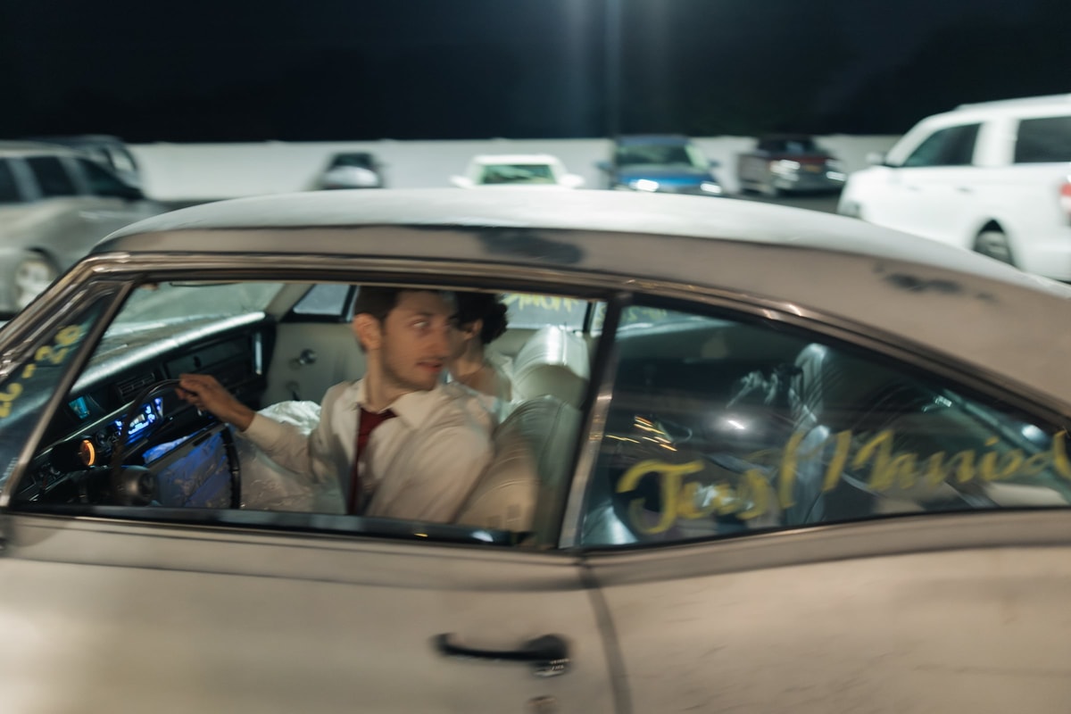 The bride and groom kiss in the back seat of the car
